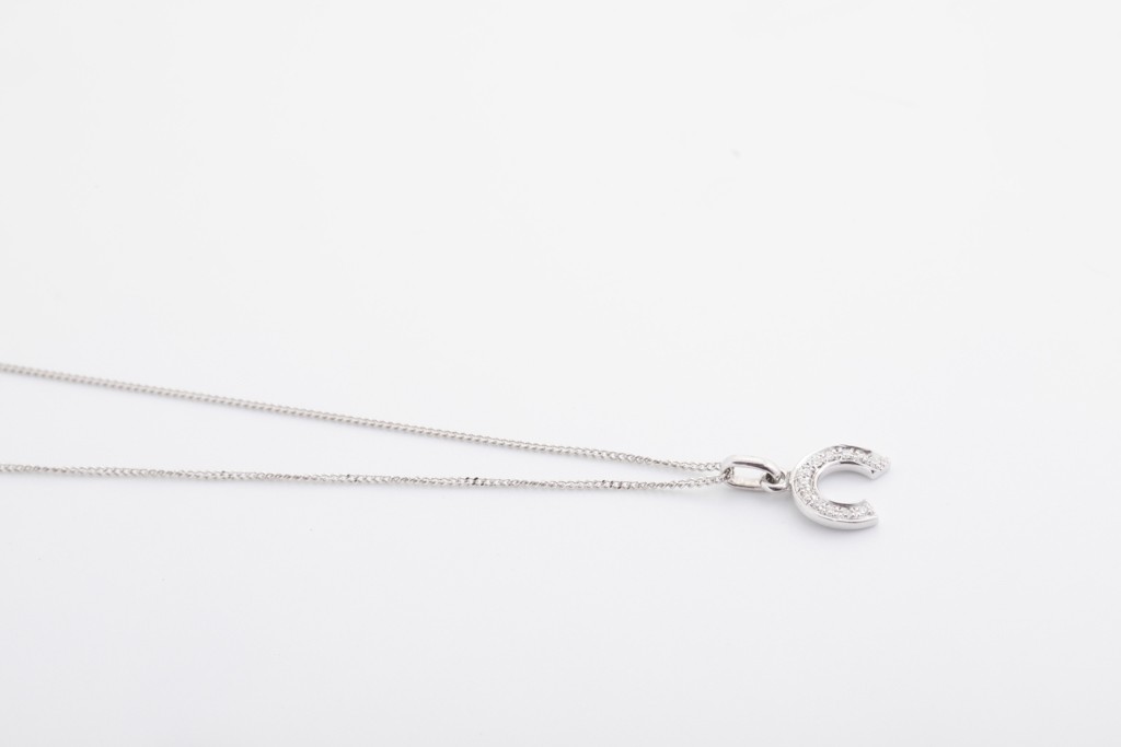 Dije tipo letra C en oro blanco de 18Kt. con diamantes.